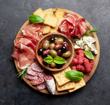 Tabla de antipasto con jamón, salami, galletas saladas, queso, aceitunas 