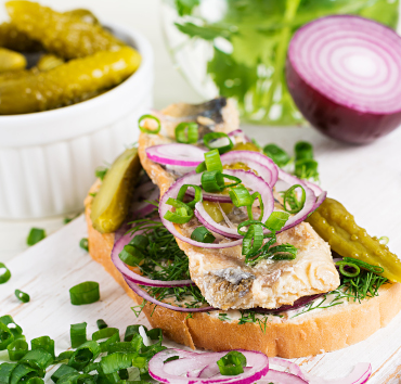 Sandwich tradicional holandés con arenque, cebolla y pepinillos